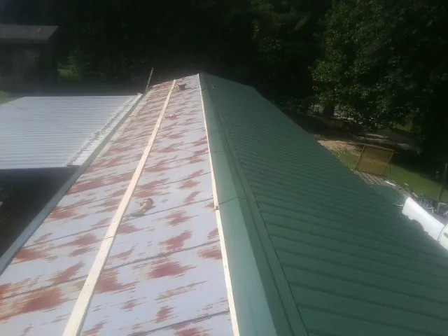 Old rusted panels beside newly installed green metal roofing — Wind Damage Roof Repair by Roofing Brothers in Pen Argyl