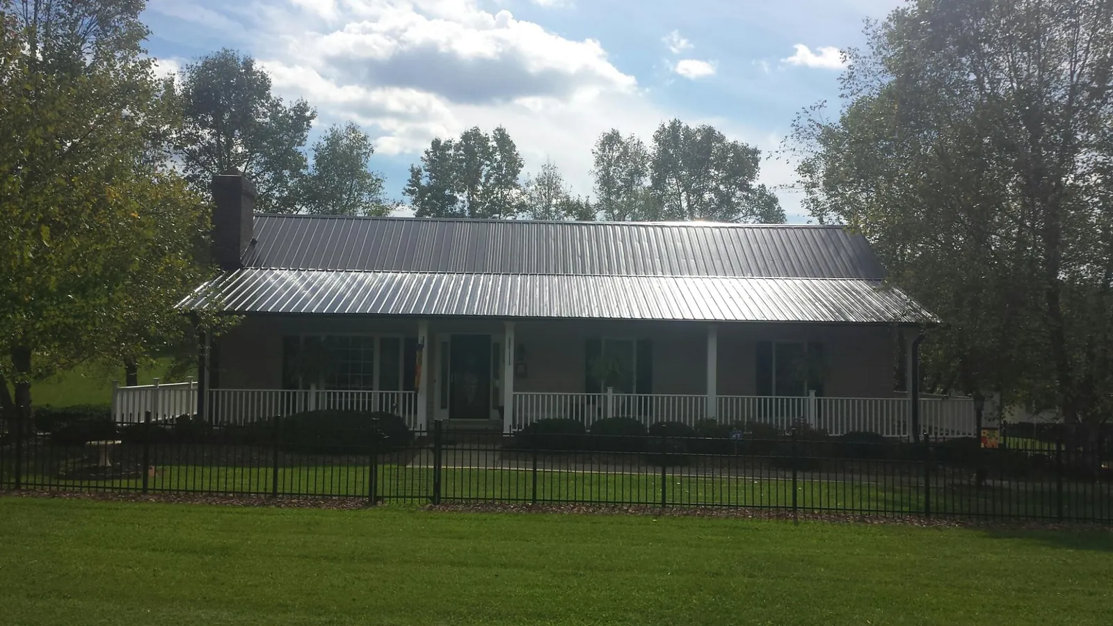 Gray metal roof on a brick ranch with a full width front porch — Gutter Guard Installation work by our crew in Pen Argyl