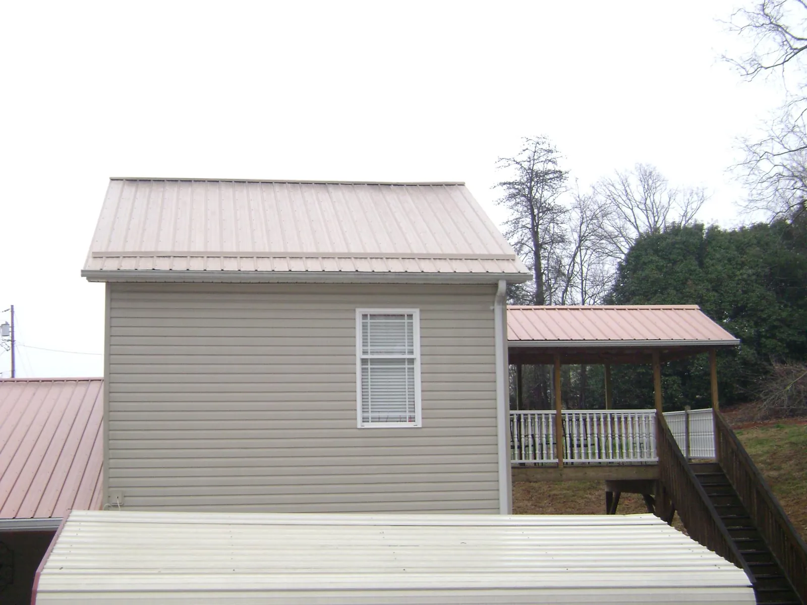 Tan metal roofs on a two story addition and attached porch, from a Roof Replacement job in Pen Argyl