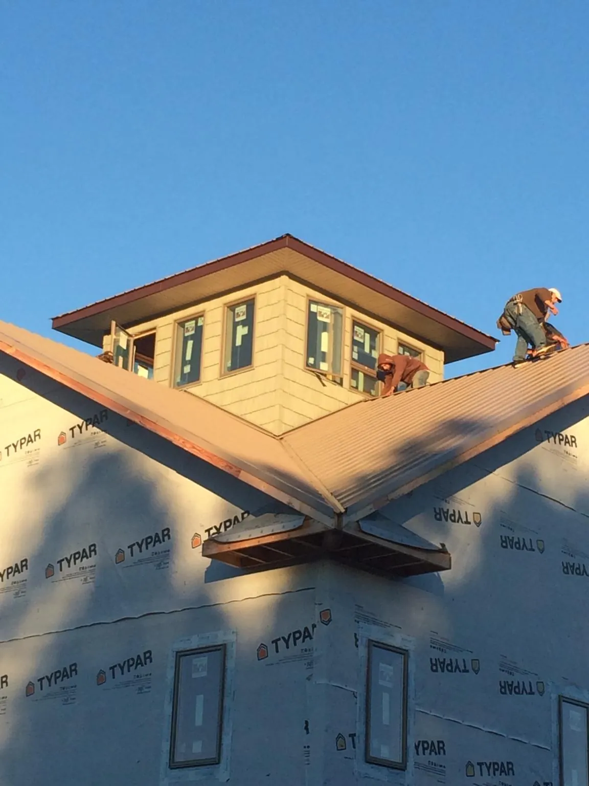 Roofers working around a rooftop cupola on a new metal roof at sunset — Roof Waterproofing in Pen Argyl by Roofing Brothers